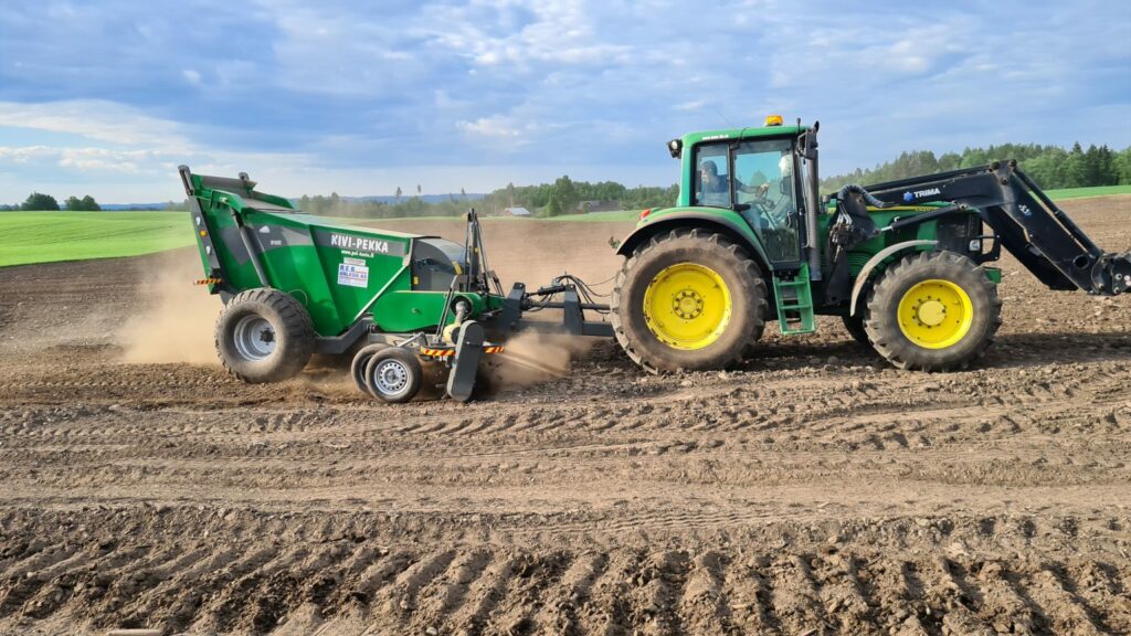 En Skanska traktor reb som pløyer et anleggsfelt med en plog.