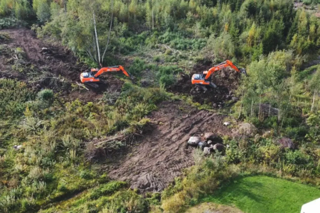 Et luftfoto av to gravemaskiner som arbeider i et felt, som utfører reb anlegg.